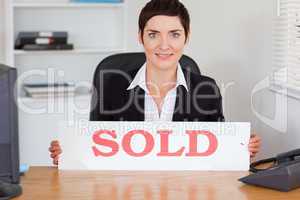 Cute real estate agent with a sold panel