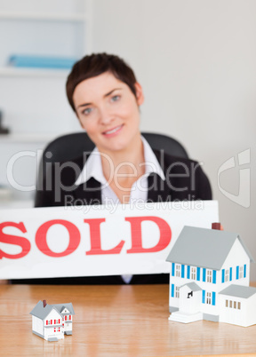 Portrait of a real estate agent with a sold panel and houses min