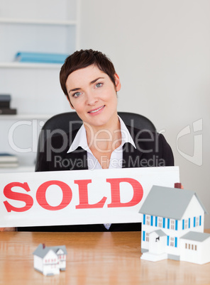 Real estate agent with a sold panel and houses miniatures