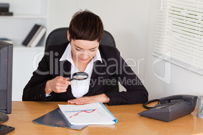 Woman looking at a chart with a magnifying glass