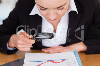 Close up of a woman looking at a chart with a magnifying glass