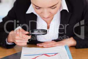 Close up of a woman looking at a chart with a magnifying glass