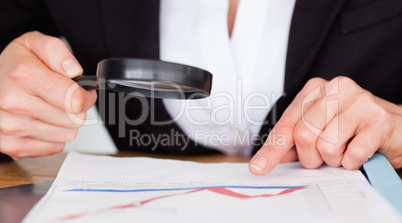 Female hands holding a magnifying glass above a chart