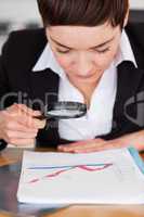 Businesswoman looking at a chart with a magnifying glass