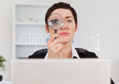 Office worker looking through  a magnifying glass