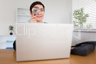Businesswoman looking through  a magnifying glass