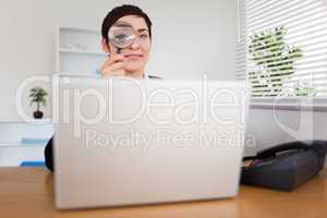 Businesswoman looking through  a magnifying glass