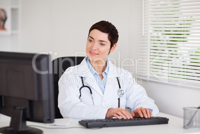 Charming doctor typing with her computer