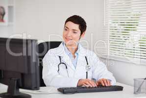 Charming doctor typing with her computer