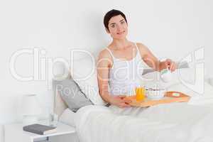 Cute woman pouring milk into her cereal