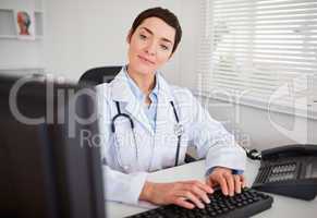 Serious female doctor looking at her computer inher office
