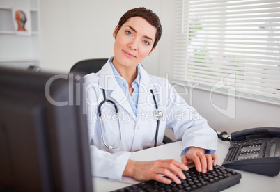 Cute female doctor typing with her computer