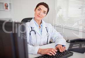 Cute female doctor typing with her computer