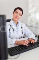 Portrait of a smiling female doctor typing with her computer