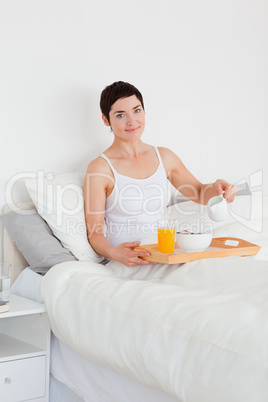 Portrait of a cute woman pouring milk into her cereal