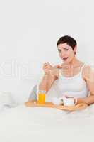 Portrait of a cute woman eating cereal while looking at the came
