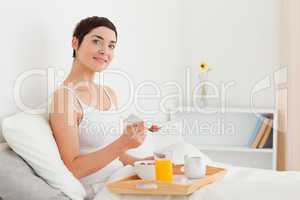 Smilling brunette eating cereal