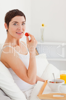 Portrait of a gorgeous brunette eating a strawberry