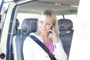 young blond woman with a smartphone on a passenger seat