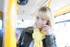young blond woman with a smartphone inside a bus