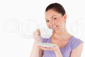 Cute woman enjoying a cup of coffee while standing