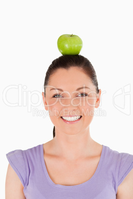 Portrait of an attractive woman holding an apple on her head whi