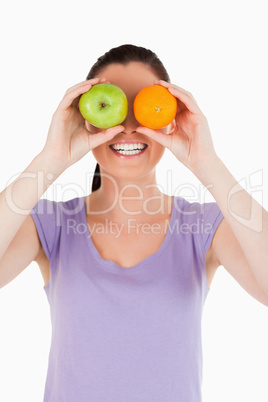 Portrait of an attractive woman playing with fruits while standi