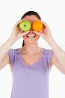 Portrait of an attractive woman playing with fruits while standi