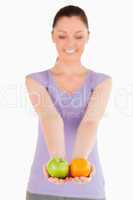 Attractive woman holding fruits while standing