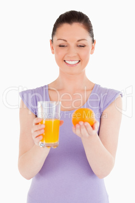 Portrait of an attractive woman holding an orange and a glass of