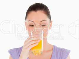 Good looking woman drinking a glass of orange juice while standi