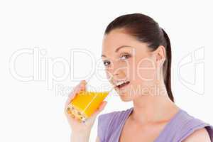 Attractive woman drinking a glass of orange juice while standing