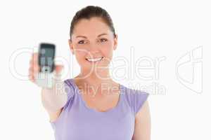 Good looking woman holding and showing her phone while standing