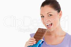 Portrait of a good looking woman eating a chocolate block while