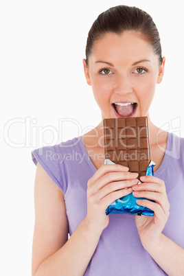 Portrait of a beautiful woman eating a chocolate block while sta