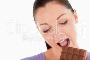 Portrait of a charming woman eating a chocolate block while stan