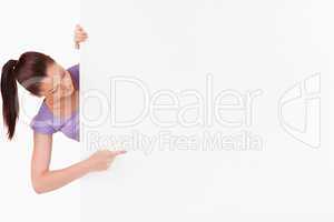 Cute female pointing at a copy space while standing