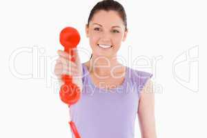 Good looking woman holding a red telephone while standing