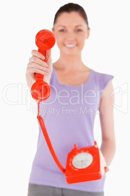 Attractive woman holding a red telephone while standing