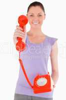 Attractive woman holding a red telephone while standing