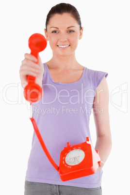 Charming woman holding a red telephone while standing