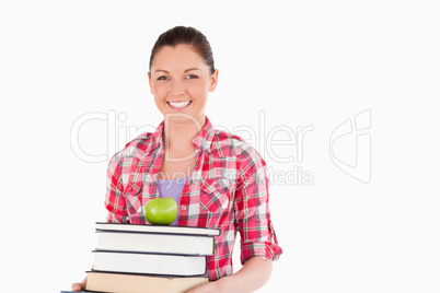 Beautiful female holding and a apple and books while posing