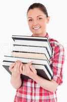 Charming female posing with books while standing