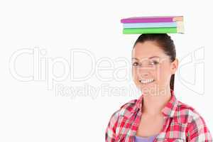 Gorgeous female holding books on her head while standing