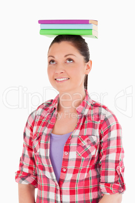 Beautiful female holding books on her head while standing