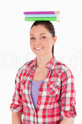 Good looking female holding books on her head while standing