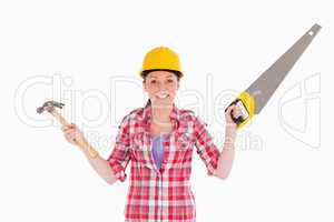 Pretty woman holding a saw and a hammer while standing