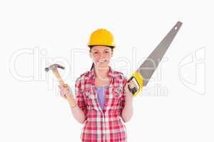 Attractive woman holding a saw and a hammer while standing