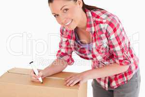 Portrait of an attractive woman writing on cardboard boxes with