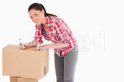 Beautiful woman writing on cardboard boxes with a marker while s